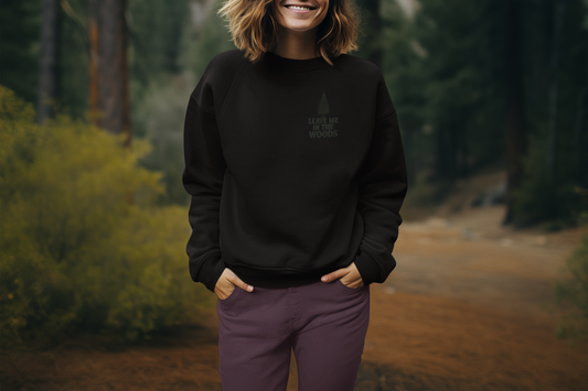 Person wearing a black sweatshirt with a logo in a forest setting