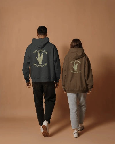 Two people wearing hoodies with text and a hand gesture on the back against a brown background