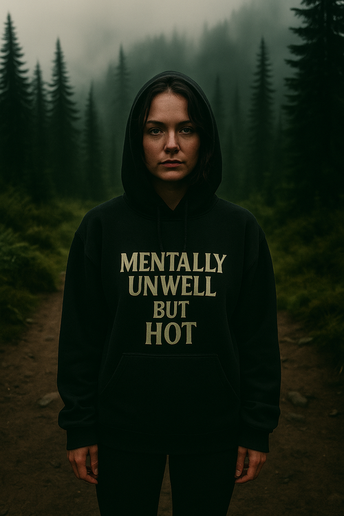 Person wearing a hoodie with 'MENTALLY UNWELL BUT HOT' text in a forest setting