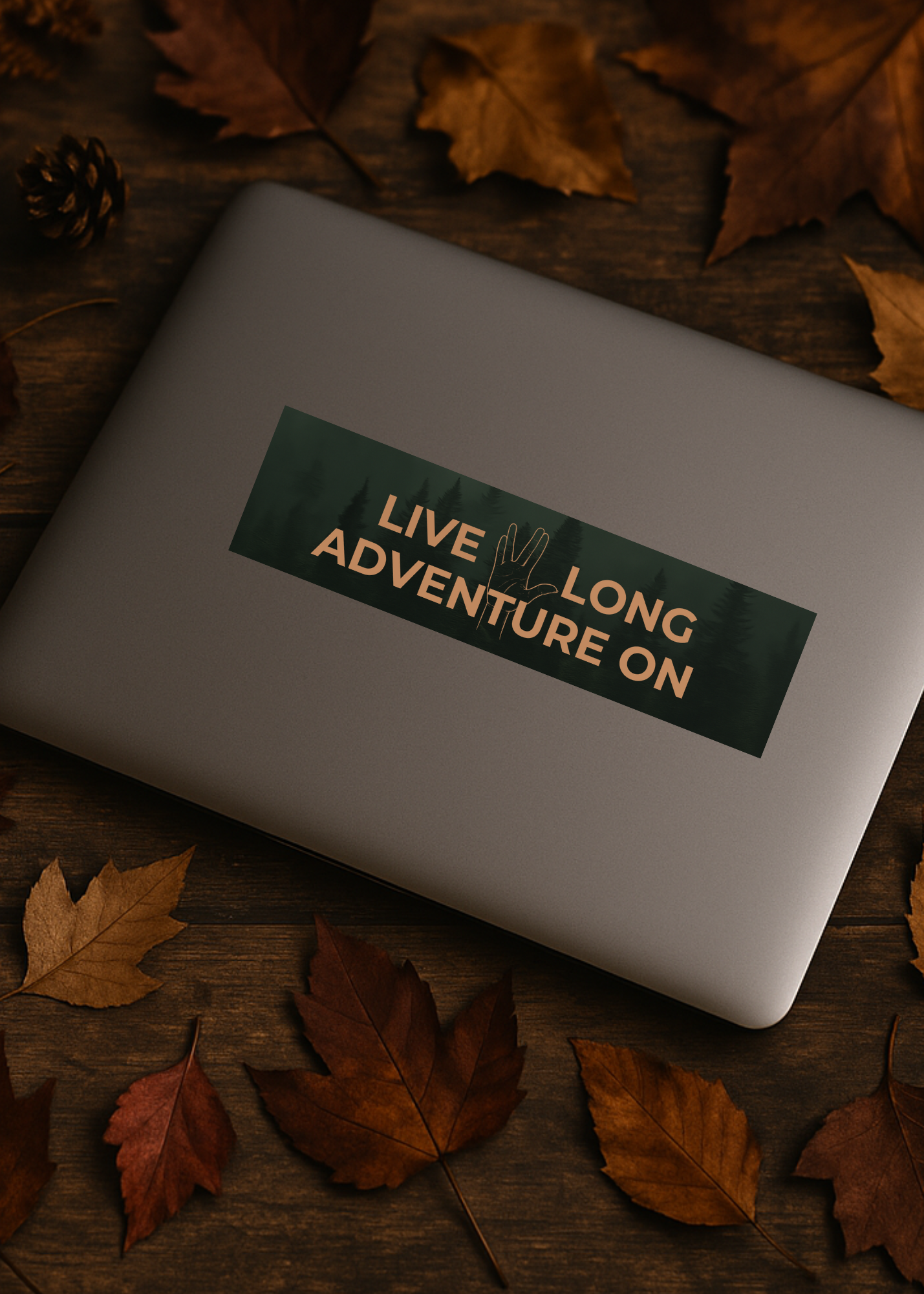 Laptop with a 'Live Long Adventure On' sticker surrounded by autumn leaves