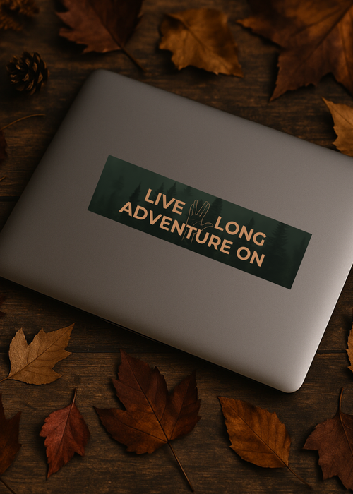Laptop with a 'Live Long Adventure On' sticker surrounded by autumn leaves