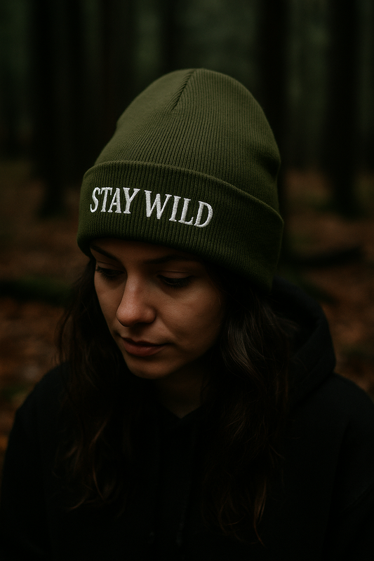 Person wearing a green 'STAY WILD' beanie in a forest setting
