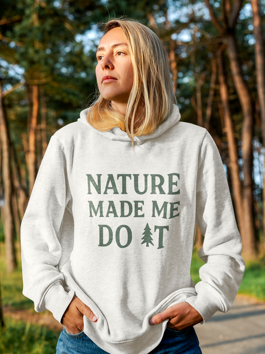 Person wearing a hoodie with 'Nature Made Me Do It' text in a forest setting