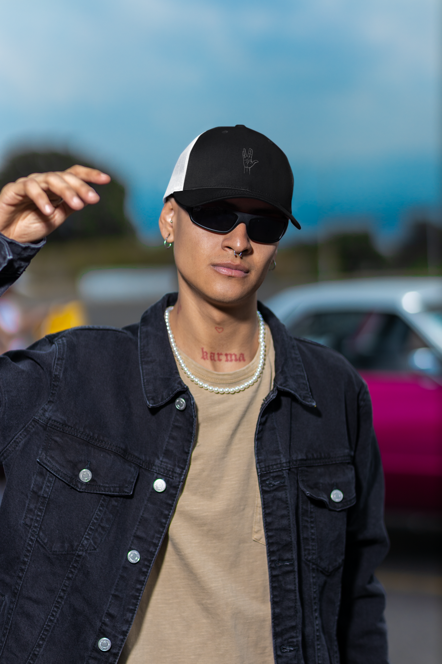 Person wearing a black cap, sunglasses, and dark jacket with a blurred background