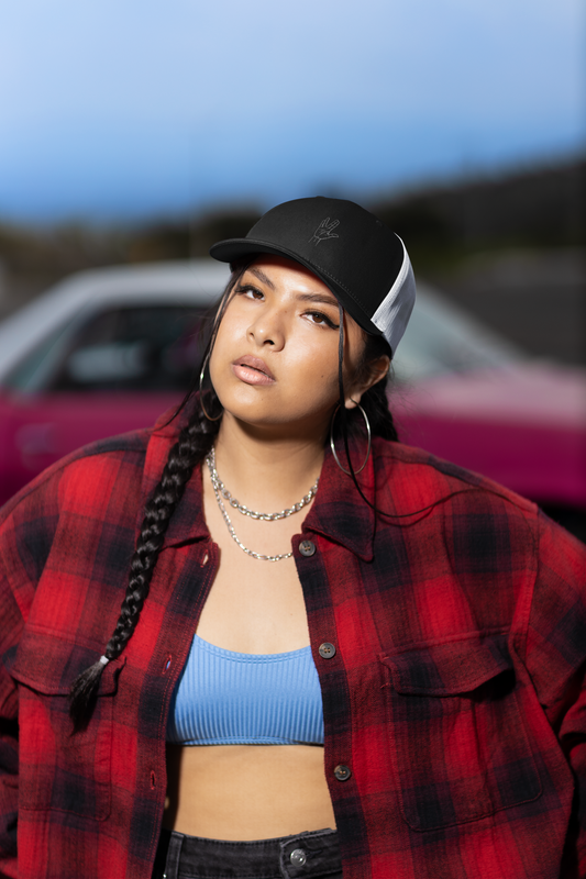 Person wearing a red plaid jacket and black cap with a blurred background